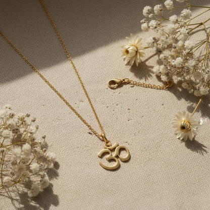 18K gold vermeil Om pendant flat lay on linen with dried white flowers