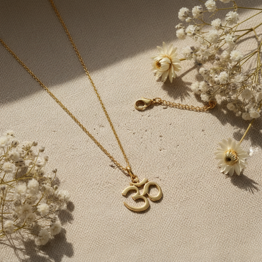 18K gold vermeil Om pendant flat lay on linen with dried white flowers